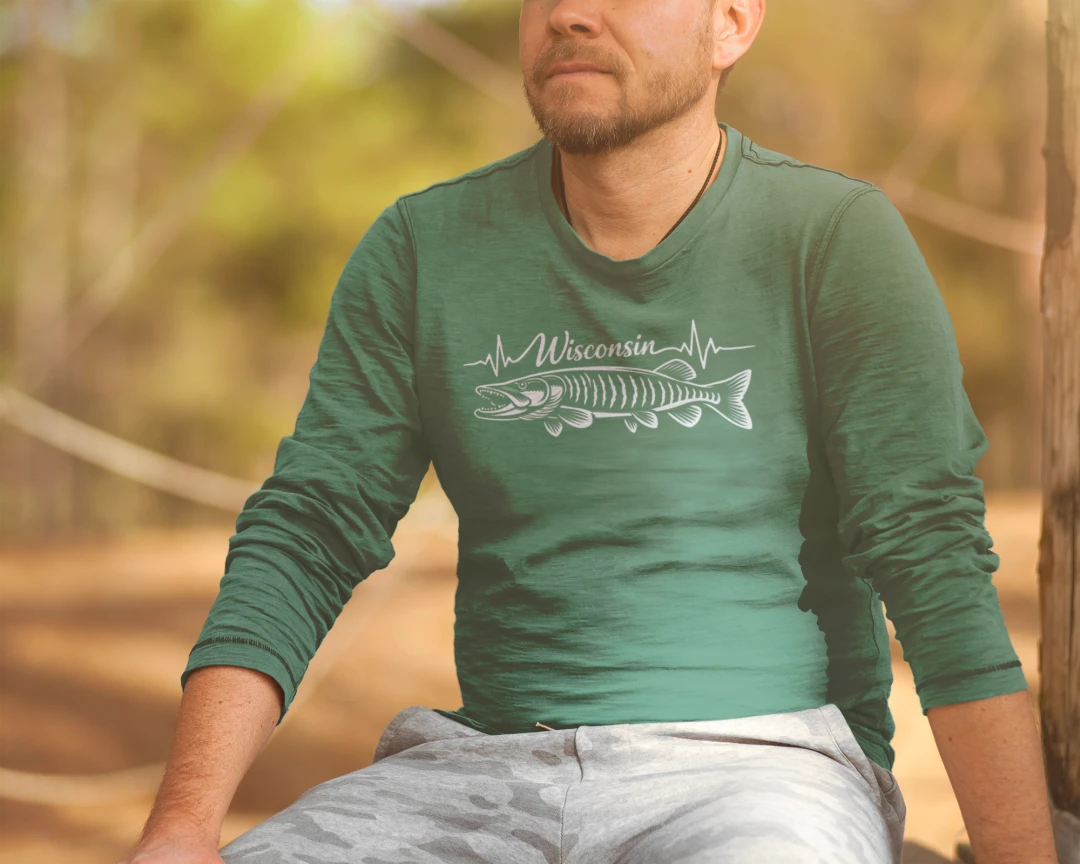 A man wearing a green long-sleeve t-shirt with a white fish skeleton and 'Wisconsin' text graphic, sitting outdoors in a wooded setting.